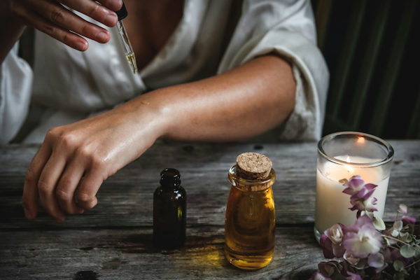 lady dropping oil onto her bare arm, surrounded by skin oils
