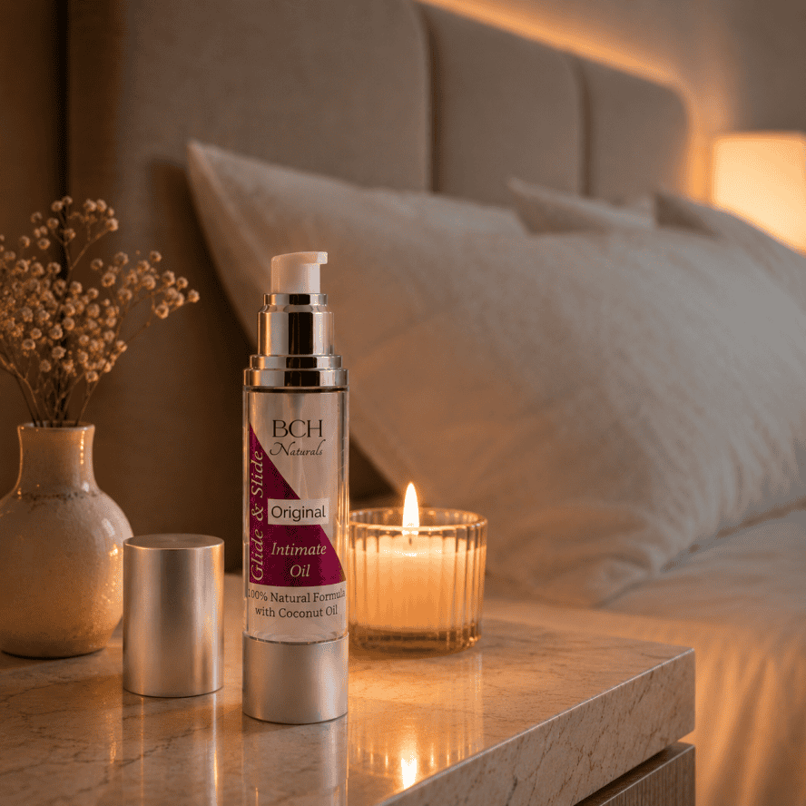 Relax with intimate oils from BCH Naturals on a bedside table next to lovely bed with a burning candle lovely scene