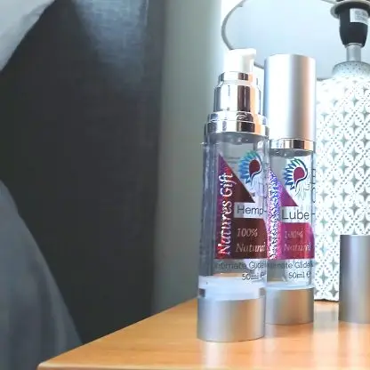BCH Naturals coconut intimate oil in a glass pump bottle, placed on a bedside table for a discreet, calming nighttime ritual