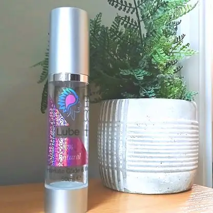 BCH Naturals coconut intimate oil styled beside a green potted plant, evoking a natural, calming home spa-like atmosphere