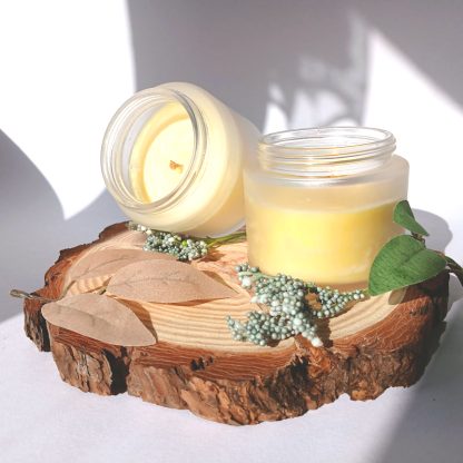 two orange candles one facing up one front on - on a slice of wood