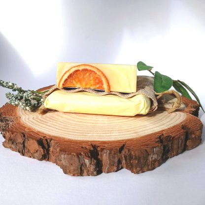 Orange Soap Bar on a Hemp Bag with yellow tissue paper on top of a slice of wood