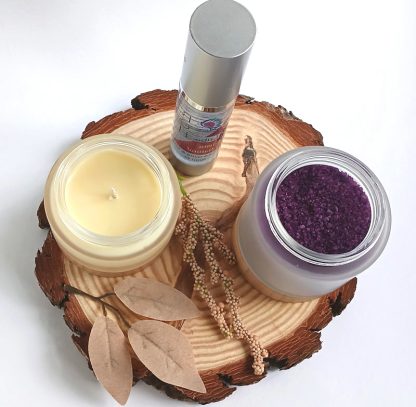 Bath Salts in a jar, with Body Glide Oil and a candle on a slice of wood