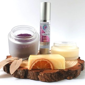 Bath Salts in a frosted Glass Jar bottle of BCH Naturals glide oil, soap and Candle on a slice of Wood with green leaves