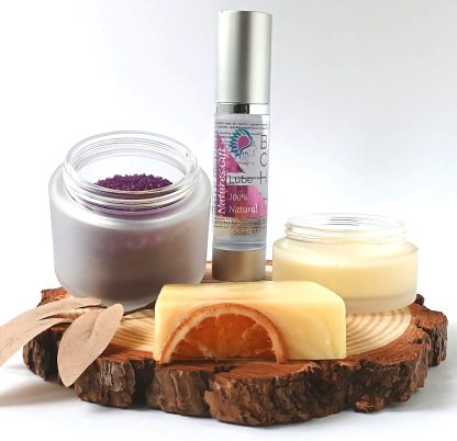 Bath Salts in a frosted Glass Jar bottle of BCH Naturals glide oil, soap and Candle on a slice of Wood with green leaves