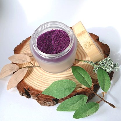 Purple Bath Salts in a jar, with Body Glide Oil and a candle on a slice of wood