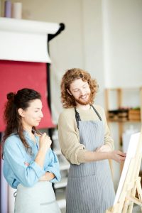 A couple wearing overalls - painting and smiling
