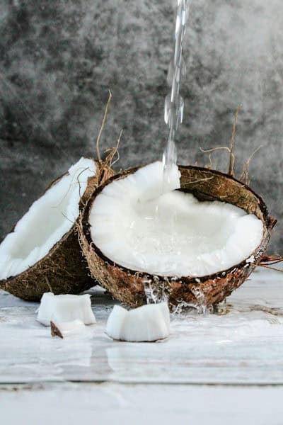Coconut oil pouring over two coconut halves