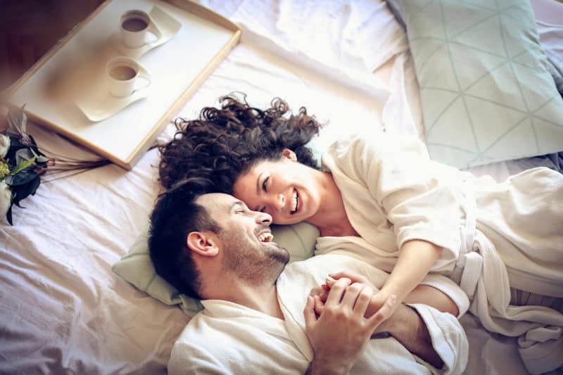 Couple relaxing together in white robes — natural intimate oil is a safer alternative to baby oil as a lubricant