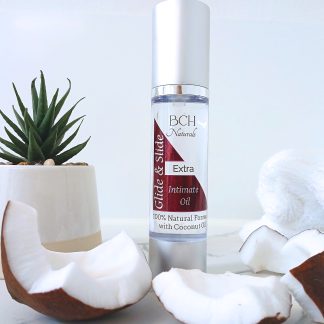 BCH Naturals Extra Glide & Slide Intimate Oil 50ml lubricant in a silver airless pump bottle, displayed on a spa-style white background with real coconut